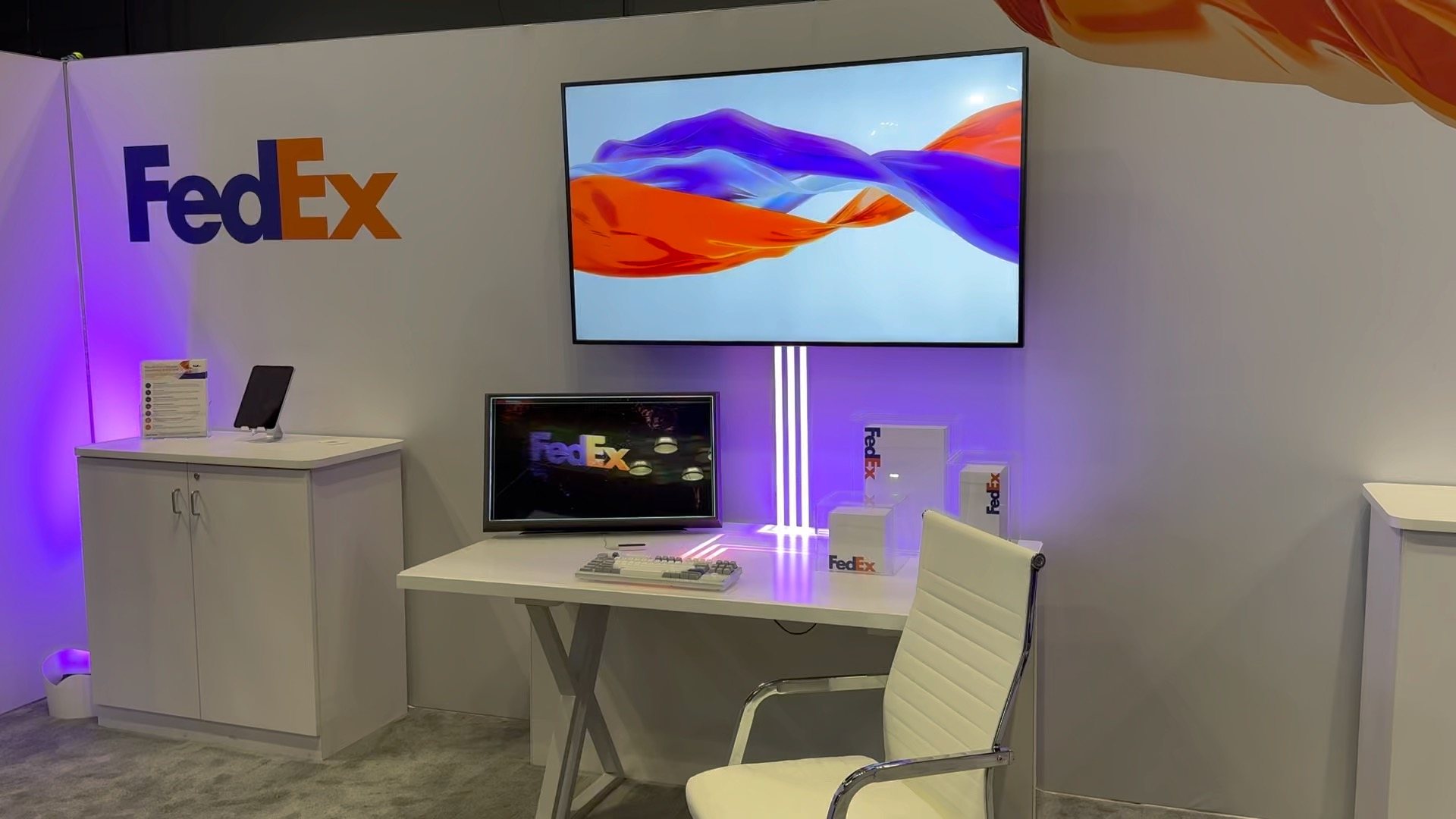 The fdx booth desk with an interactive display, light lines and FedEx packaging
