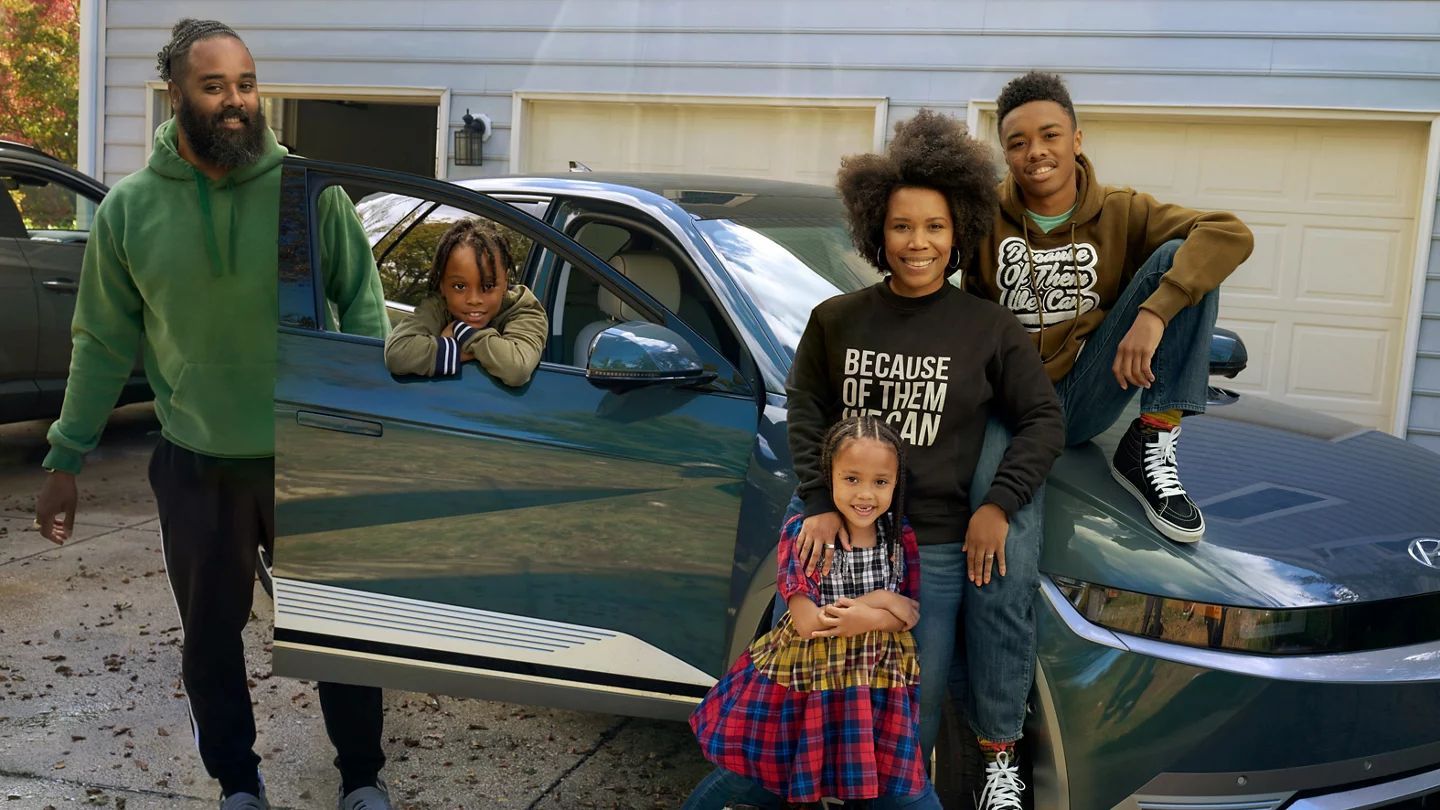 A family gathered around their car on a driveway