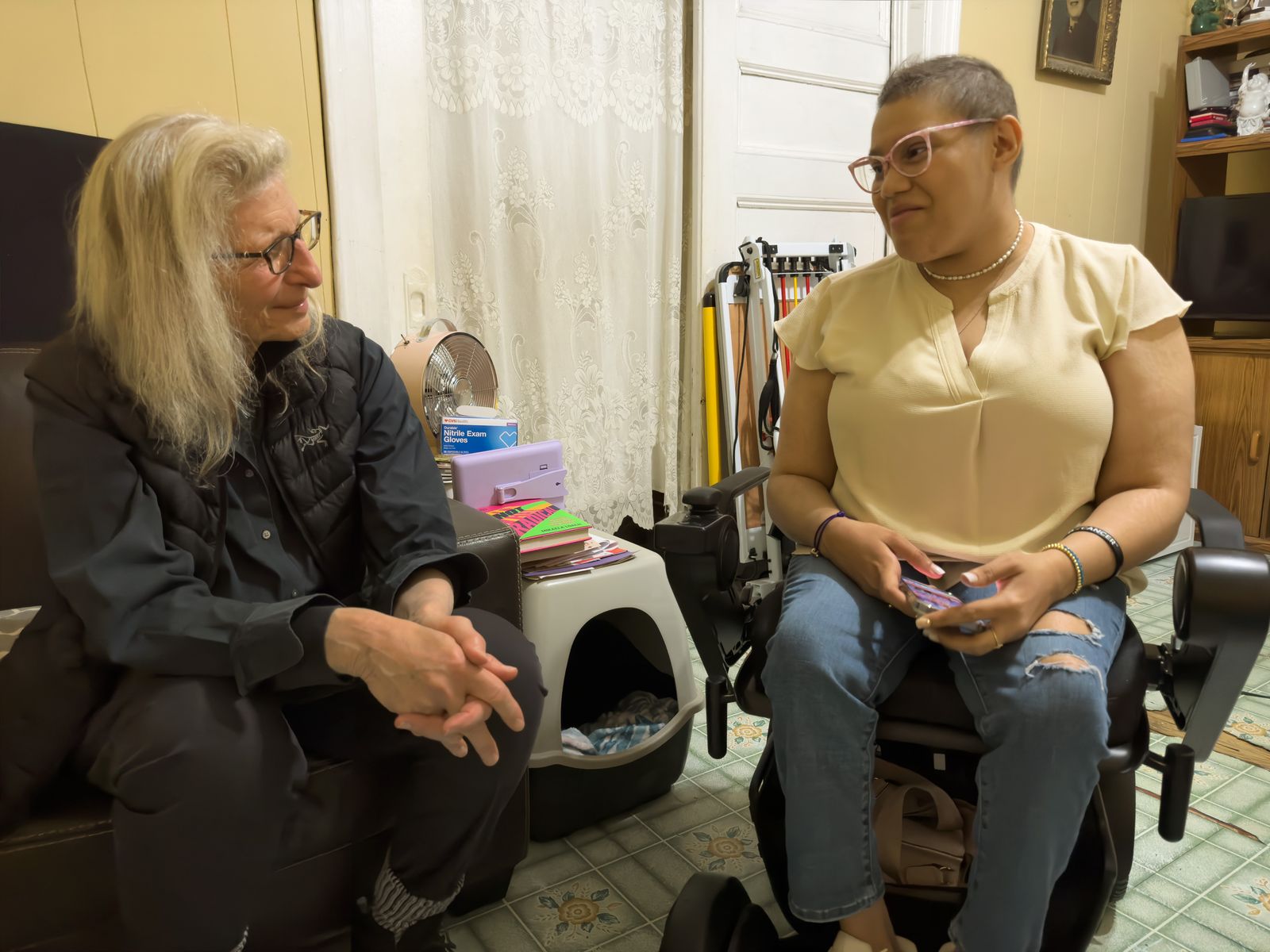 Annie Leibovitz talks with a woman seated in her wheelchair in her living room before the shoot