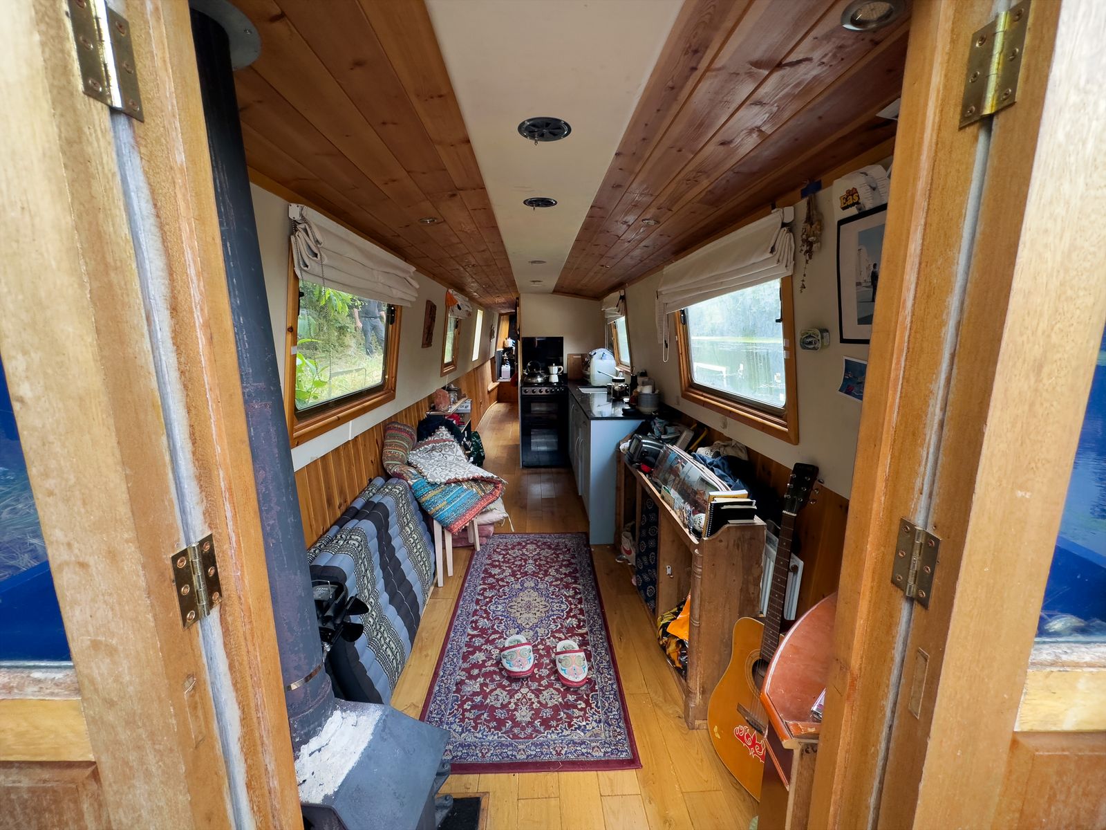 Looking through the doors into a narrowboat home with a rug, sofa and wood-panelled ceiling