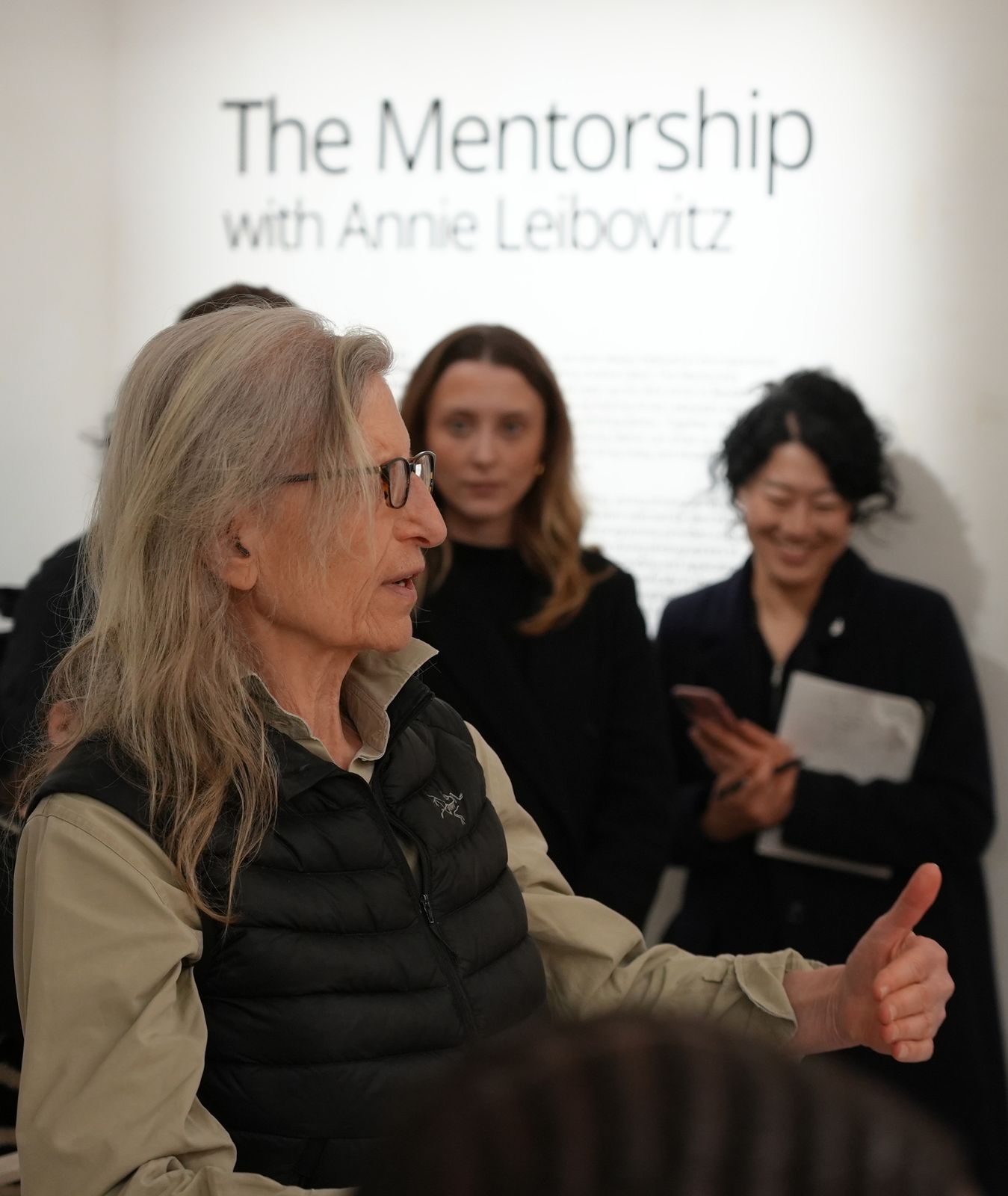 Annie Leibovitz talks with guests beneath The Mentorship with Annie Leibovitz wall text