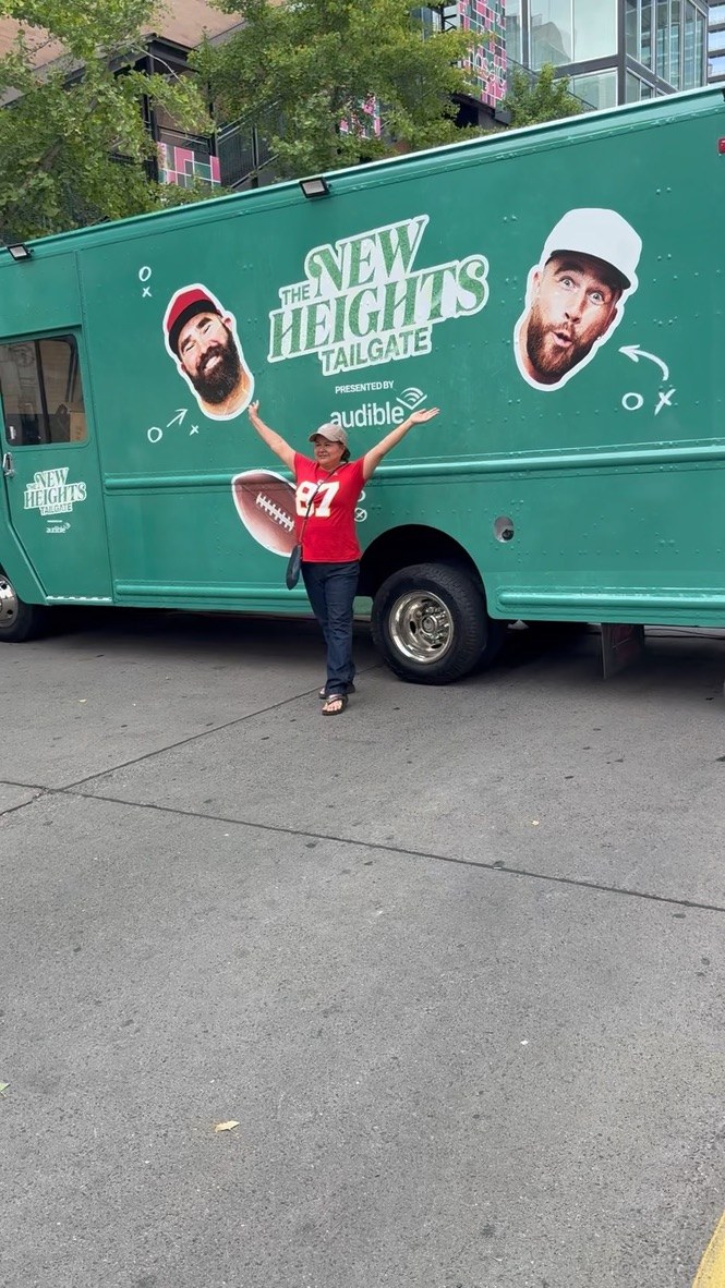 A fan celebrating in front of the wrapped Tailgate truck, presented by Audible