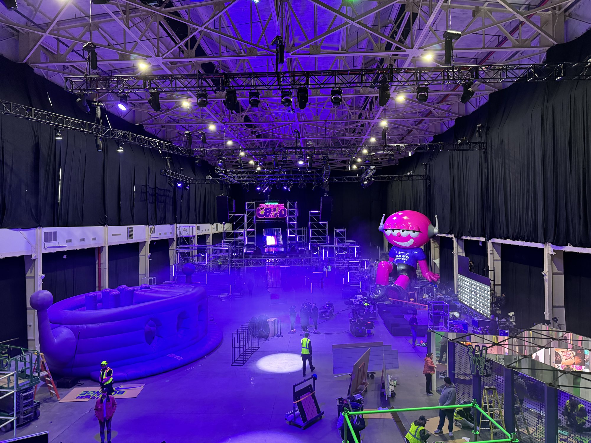 Crew finishing the Dynamic Land hall before doors, with the stage and giant inflatable behind