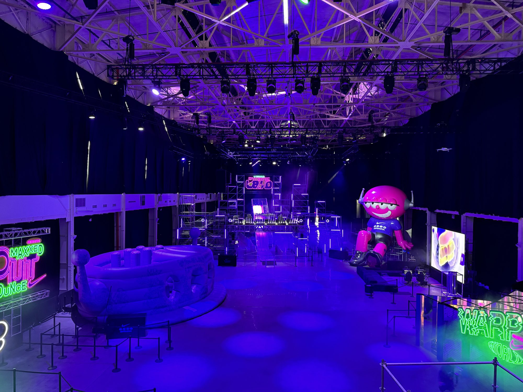 The Dynamic Land hall under purple light, with the giant Air Max character and neon signs