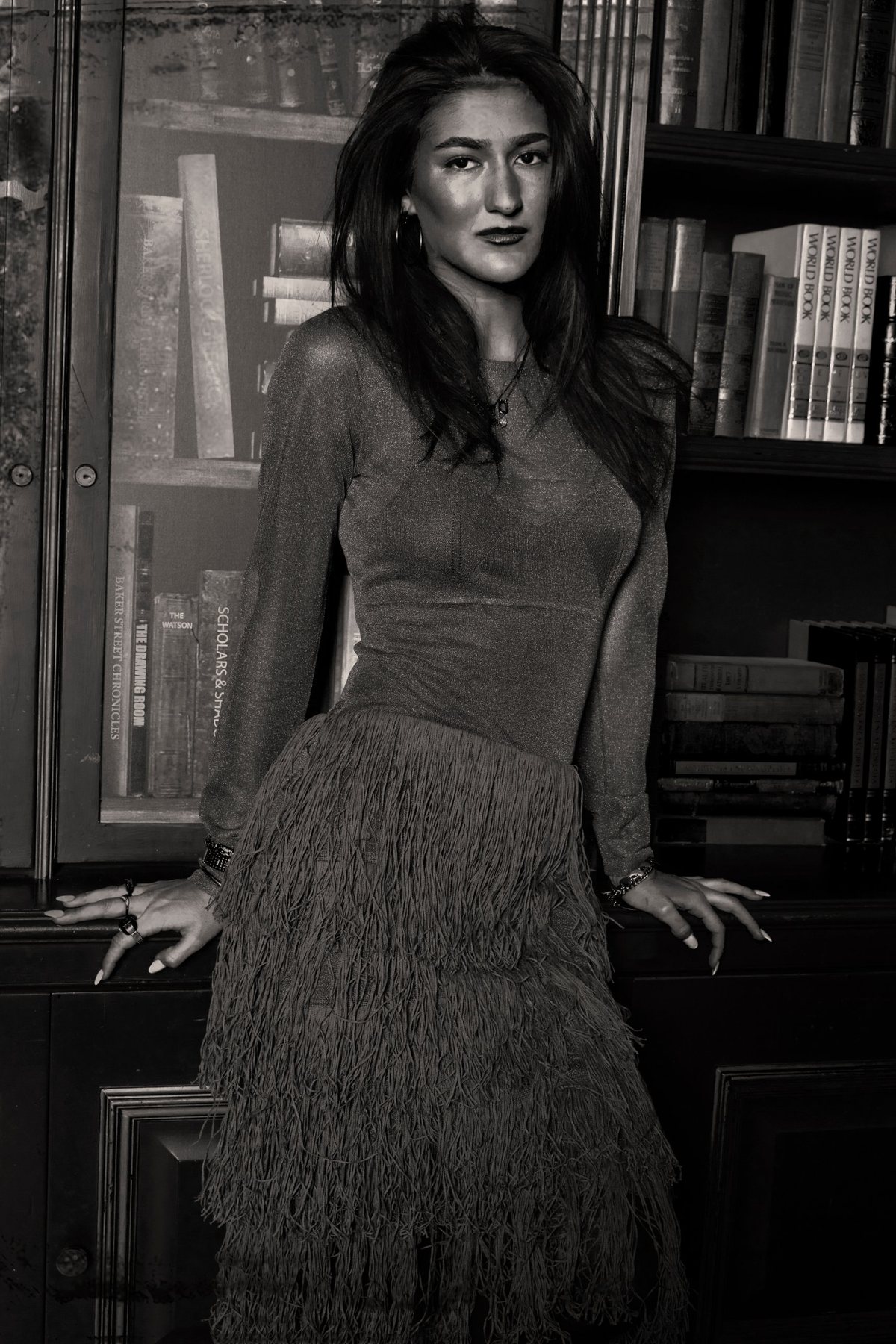 A creator in a fringed dress against the library shelves