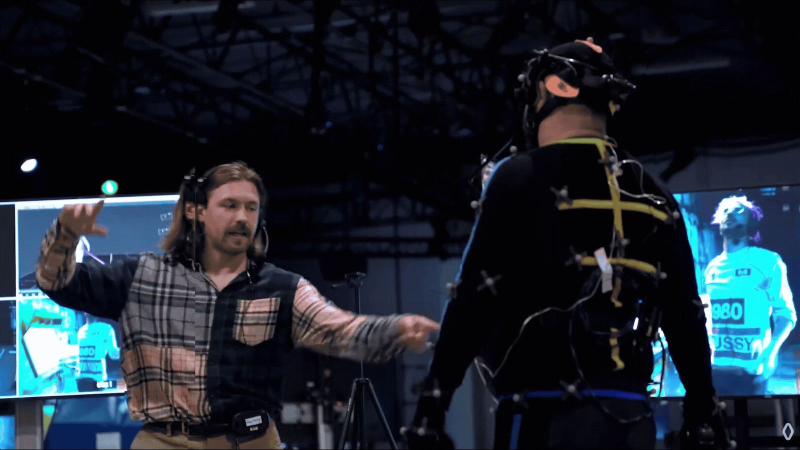 A director works with a performer in a motion capture suit on the stage