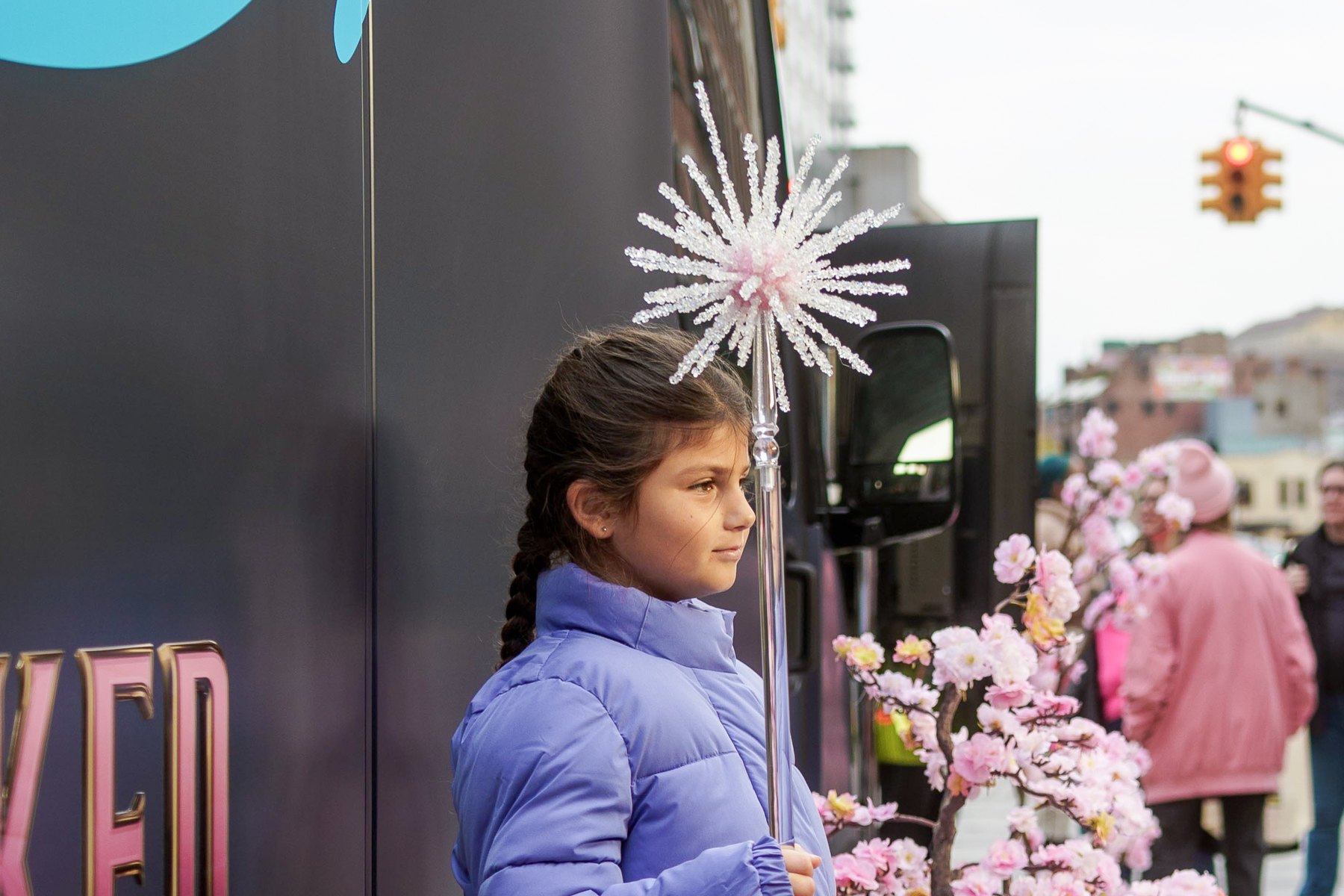 A young fan holds a Glinda wand beside the Wicked Prime Van